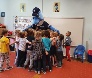 Dzieci przytulają Polfinka w sali przedszkola.