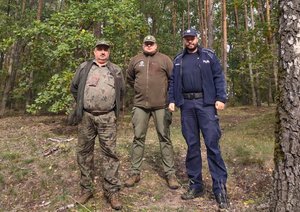 Policjant i leśnicy w terenie leśnym.