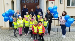 Wspólne zdjęcie policjantów, dzieci i ich opiekunów na schodach Komendy Miejskiej Policji w Bydgoszczy.