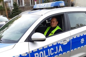 policjant post. Łukasz Łusiak siedzi w oznakowanym radiowozie