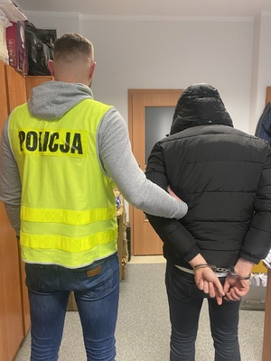 policjant stoi z zatrzymanym- ujęcie z tyłu