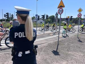 policjantka ruchu drogowego przygląda się jeździe dzieci po miasteczku ruchu drogowego