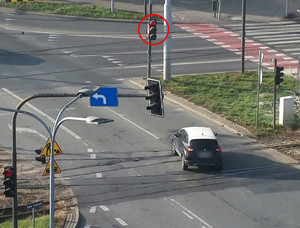 widok na rondo, na którym widać auto przejeżdżające na czerwonym świetle