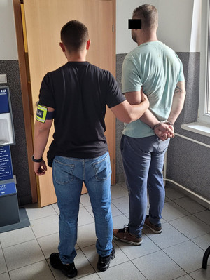 Policjant stoi wraz z zatrzymanym.