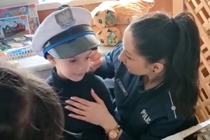 policjantka maluje twarz chłopcu. Chłopiec ma na głowie założoną czapkę policjanta ruchu drogowego