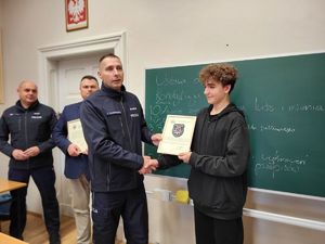 komendant wręczający emblemat policyjny uczniowi klasy policyjnej