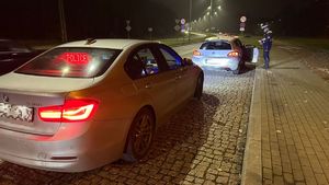 policjant stojący przy zatrzymanym do kontroli pojeździe i wykonuje czynność legitymowania