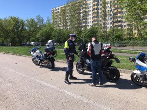 umundurowany policjant kontroluje na drodze motocyklistę