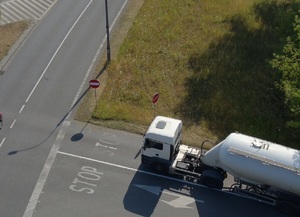 Zdjęcie przedstawia widok z góry zrobiony policyjnym dronem na skrzyżowaniu, gdzie obowiązuje znak B-20 STOP. Widać pojazd ciężarowy z rejonie skrzyżowania