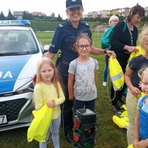 policjantka stoi z dziećmi przy radiowozie