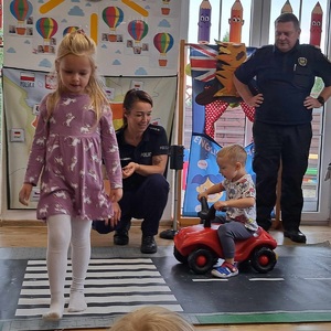 dziecko przechodzi przez pasy, policjantka pokazuje jak to zrobić