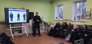 policjant prowadzi zajęcia na tablicy prezentowane rodzaje umundurowania
