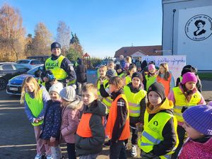 policjant stoi z dziećmi przy radiowozie