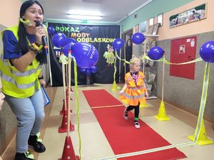 dziecko idzie po wybiegu obok prowadząca mówi do mikrofonu