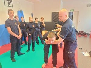policjant pokazuje uczniom chwyt obezwładniający