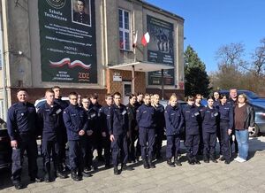 policjanci stoją z klasą policyjną przed szkołą