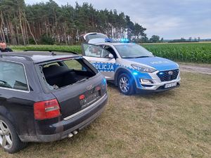 policyjny radiowóz stoi obok uszkodzonego auta