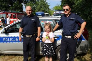 Policjanci i dziecko przy radiowozie