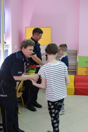 dzieci wręczają policjantom laurkę i kwiatek