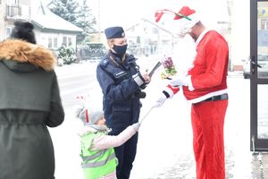 dziewczynka z policjantka wręcza Mikołajowi odblask
