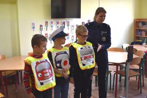 policjantka i dzieci w kamizelkach służb ratunkowych