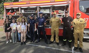 policjanci i strażacy z dziećmi przy pojeździe bojowym straży pożarnej