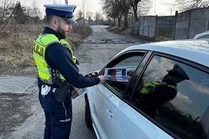 policjant wręcza kierowcy ulotkę