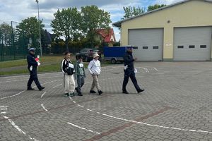 policjanci wyjaśniają uczniom pokonanie miasteczka ruchu drogowego