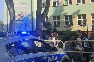 radiowóz na sygnale przy szkole, w tle idące dezieci