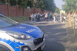 radiowóz policyjny, policjant przy przejściu po którym idą uczniowie