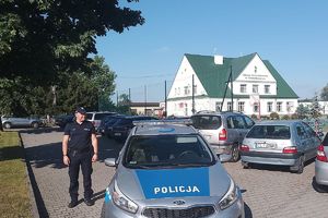 policjant obok radiowozu przy szkole