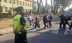 policjant przepuszcza dzieci przez przejście dla pieszych przy szkole