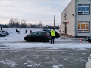 Policjant przed szkołą obserwuje ruch pojazdów
