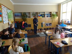 policjantka uczy dzieci siedzące w sali znaczenia sygnałów drogowych