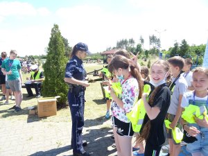 policjantka rozdaje dzieciom odblaskowe opaski