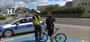 policjant przekazuje kamizelkę odblaskową kontrolowanemu rowerzyście