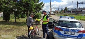 policjant daje kamizelkę rowerzyście