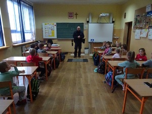 policjant prowadzi zajęcia dla dzieci siedzących w klasie