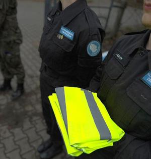 policjanci i uczniowie rozdają odblaski