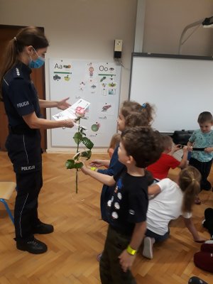 dzieci wręczają kwiatek policjantce i dziękują za spotkanie