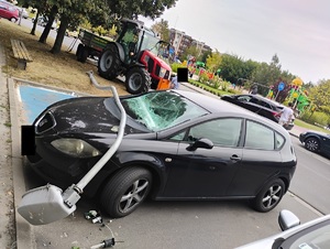 uszkodzony samochod osobowy, na którym lezy przewrócona latarnia