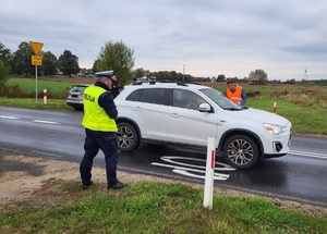 pracownik kolei wręcza ulotkę kierowcy samochodu przy przejeżdzie kolejowym