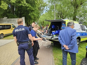 Policjanci pokazują sprzęt służbowy, dziecko trzyma w ręku broń