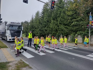 dzielnicowy wspólnie z dziećmi przechodzi przez przejście dla pieszych