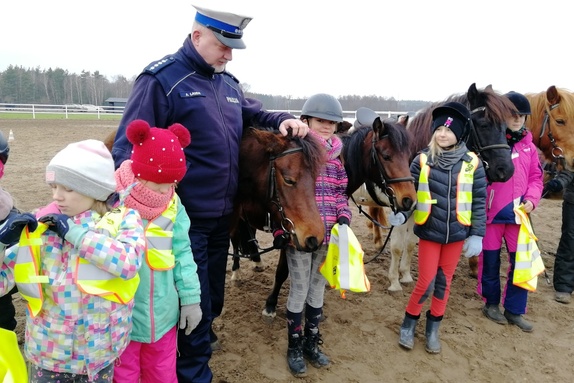 Policjant stoi między dziećmi i zwierzętami