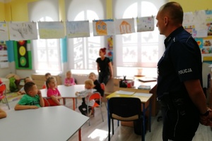 Policjant stoi skierowany w stronę dzieci
