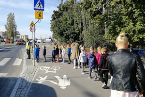 Dzieci idą za policjantem w stronę przejścia dla pieszych