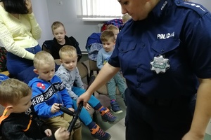 Policjantka pokazuje przedszkolakom pałkę słuzbową