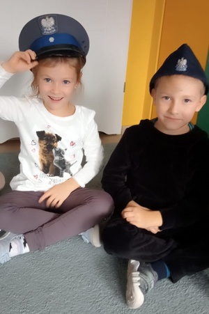 Dzieci z założonymi na głowie czapkami policjanta