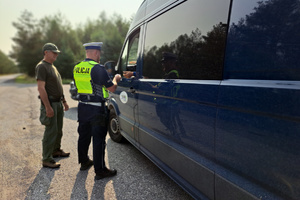 Policjant wspólnie ze Strażnikiem Leśnym prowadzą kontrolę pojazdu